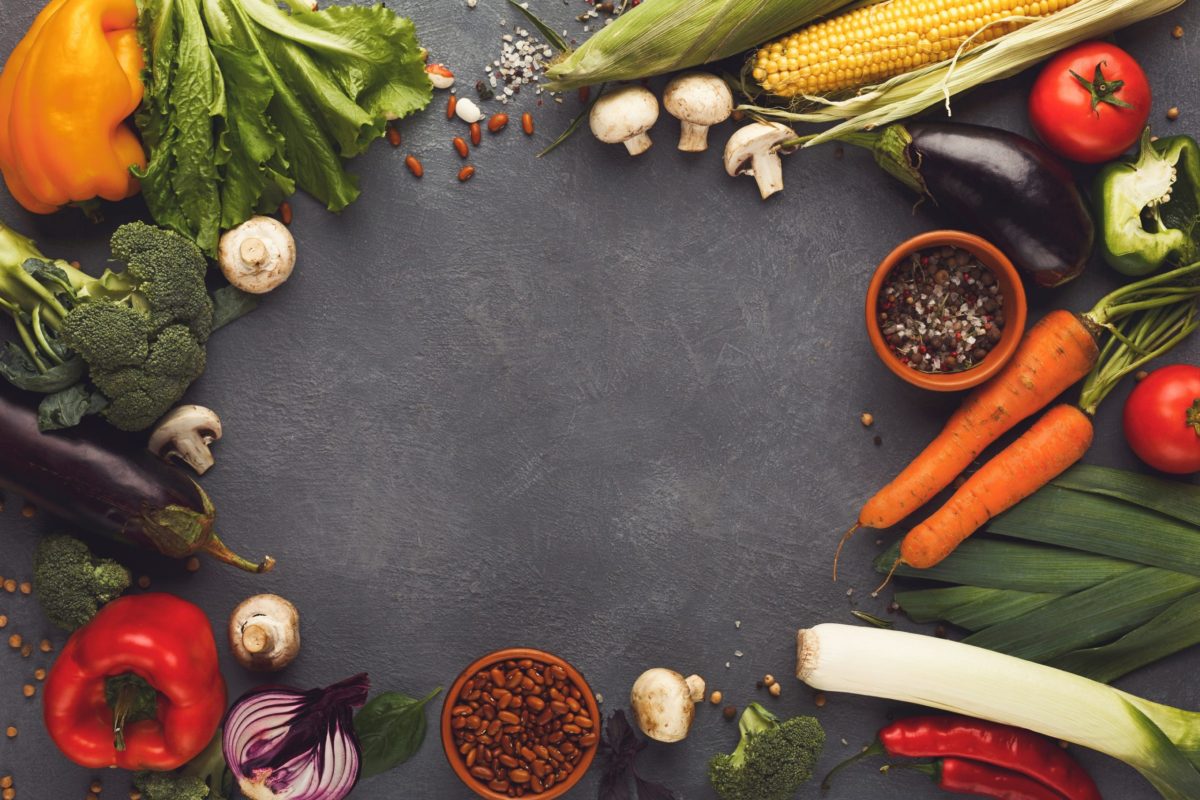 frame of fresh very colourful veg on a wooden background